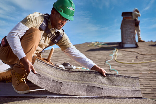 roofer holding shingle on roof