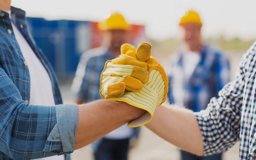 contractor and roofer shaking hands on work site