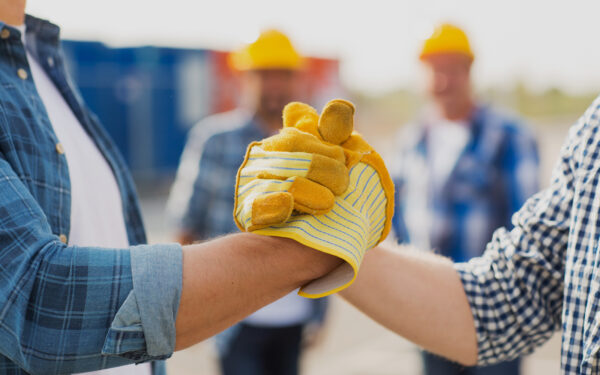 contractor and roofer shaking hands on work site